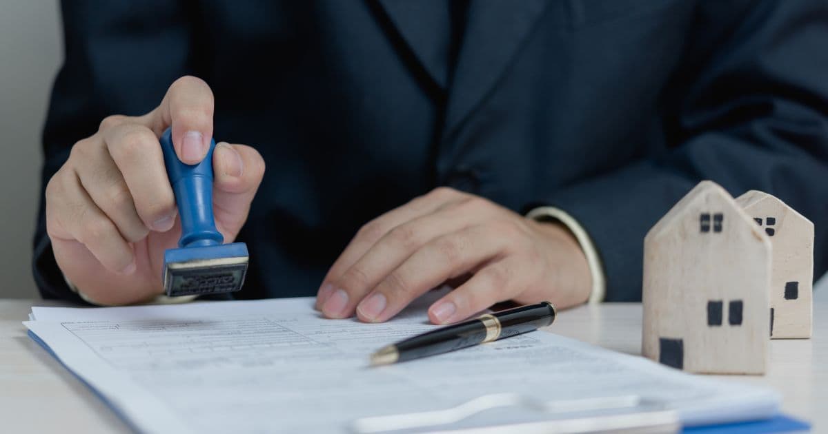 Real estate agent stamping property approval documents beside house model